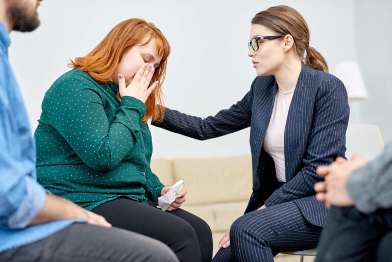 A woman engages in conversation with a man and another woman, all three appearing attentive and interested.